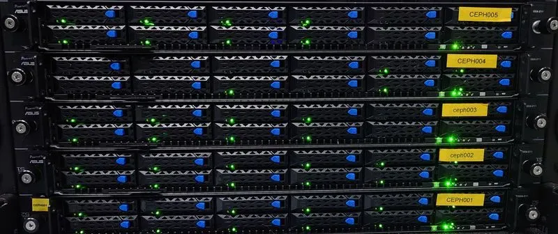 Server racks with active green-lit status indicators and labels in a data center. The server fronts display blue and yellow markings identifying the different units