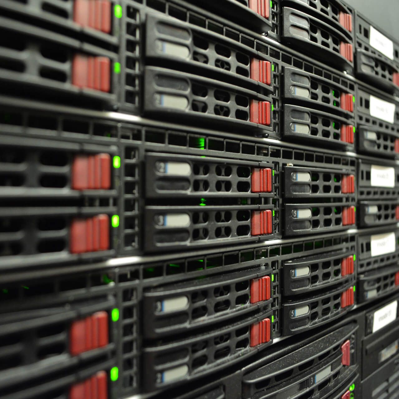 Close-up view of several black server racks with red details and green indicator lights, used for data storage and processing