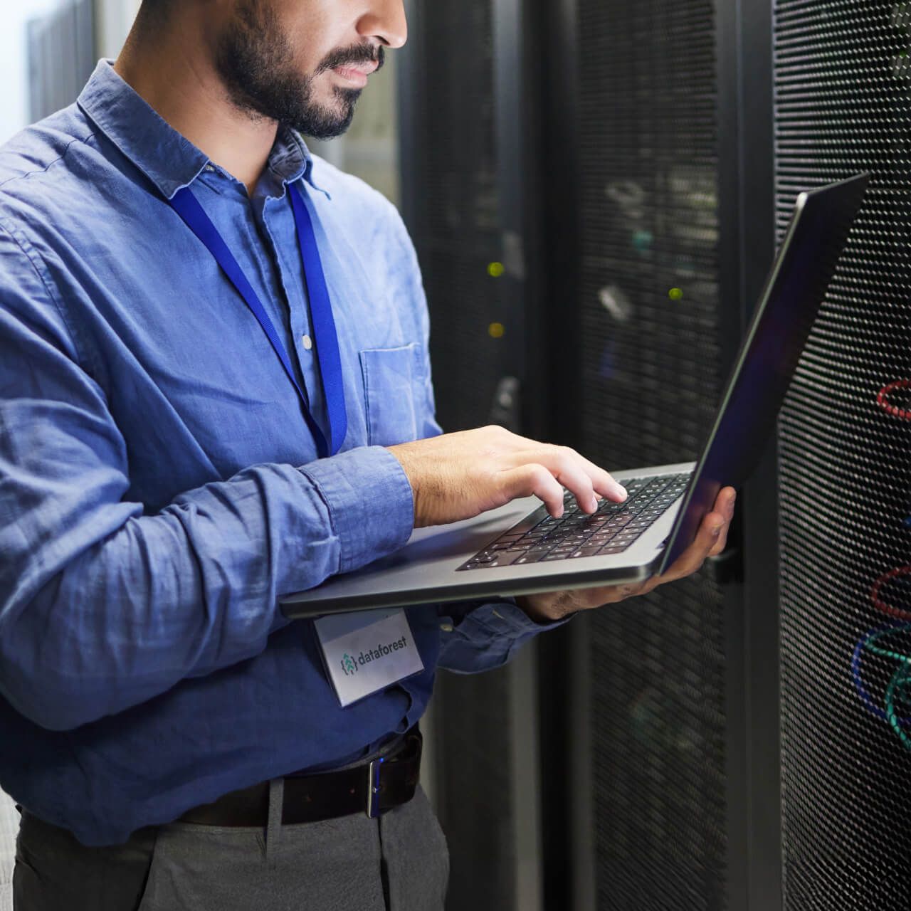 An IT technician working on a laptop in a server room